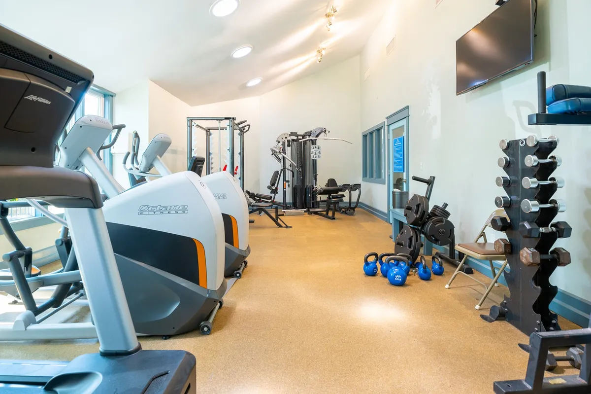 A modern fitness center filled with treadmills, multi-gym equipment, kettlebells, and dumbbells. The space is bright and organized, inviting residents to pursue fitness goals regardless of the season.